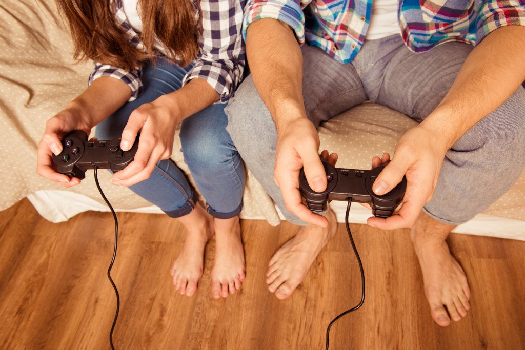 Junges Paar sitzt auf dem Sofa und hält Gamepads in der Hand